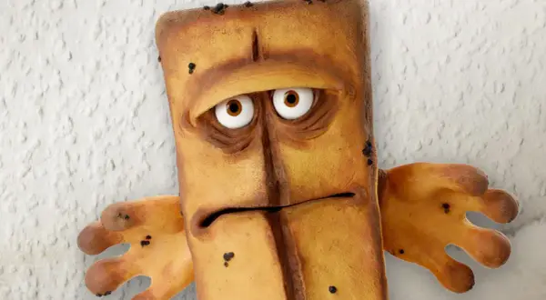 Smutny Bernd das Brot, z wielkimi oczami i wyrazem twarzy pełnym zmartwienia, stoi na tle chropowatej ściany.