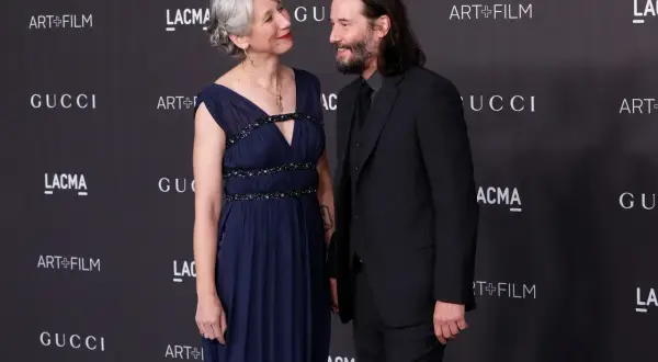 Alexandra Grant wzrost jest widoczny obok Keanu Reevesa. Oboje pozują na tle logo Gucci i Art+Film.