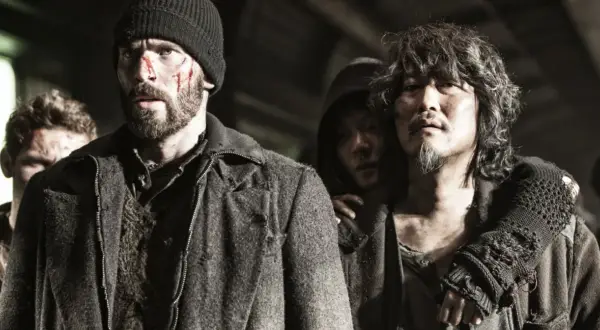 Zraniona obsada Snowpiercer: Arka przyszłości, w tym Chris Evans, w surowych, postapokaliptycznych strojach.