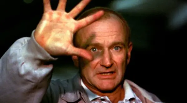 Robin Williams, który zdobył Oscara za rolę w "Buntowniku z wyboru", z dłonią przed twarzą.