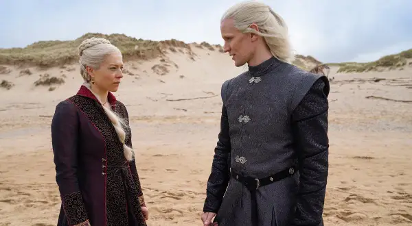 Rhaenyra i Daemon Targaryenowie, bohaterowie "Ród smoka", stoją na piaszczystej plaży, wpatrzeni w siebie.