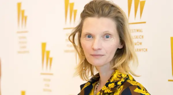 Agata Buzek, znana z imponującego wzrostu, w barwnej stylizacji z błyszczącymi akcentami na twarzy.