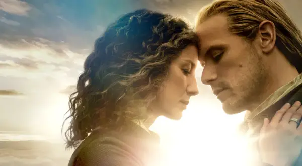 Claire i Jamie, bohaterowie serialu Outlander, z czołami dotykającymi się na tle nieba.