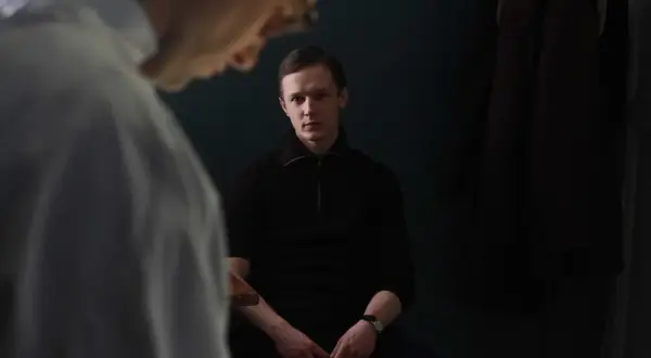 Filip Pławiak siedzi w ciemnym pomieszczeniu, wpatrując się wprost przed siebie.