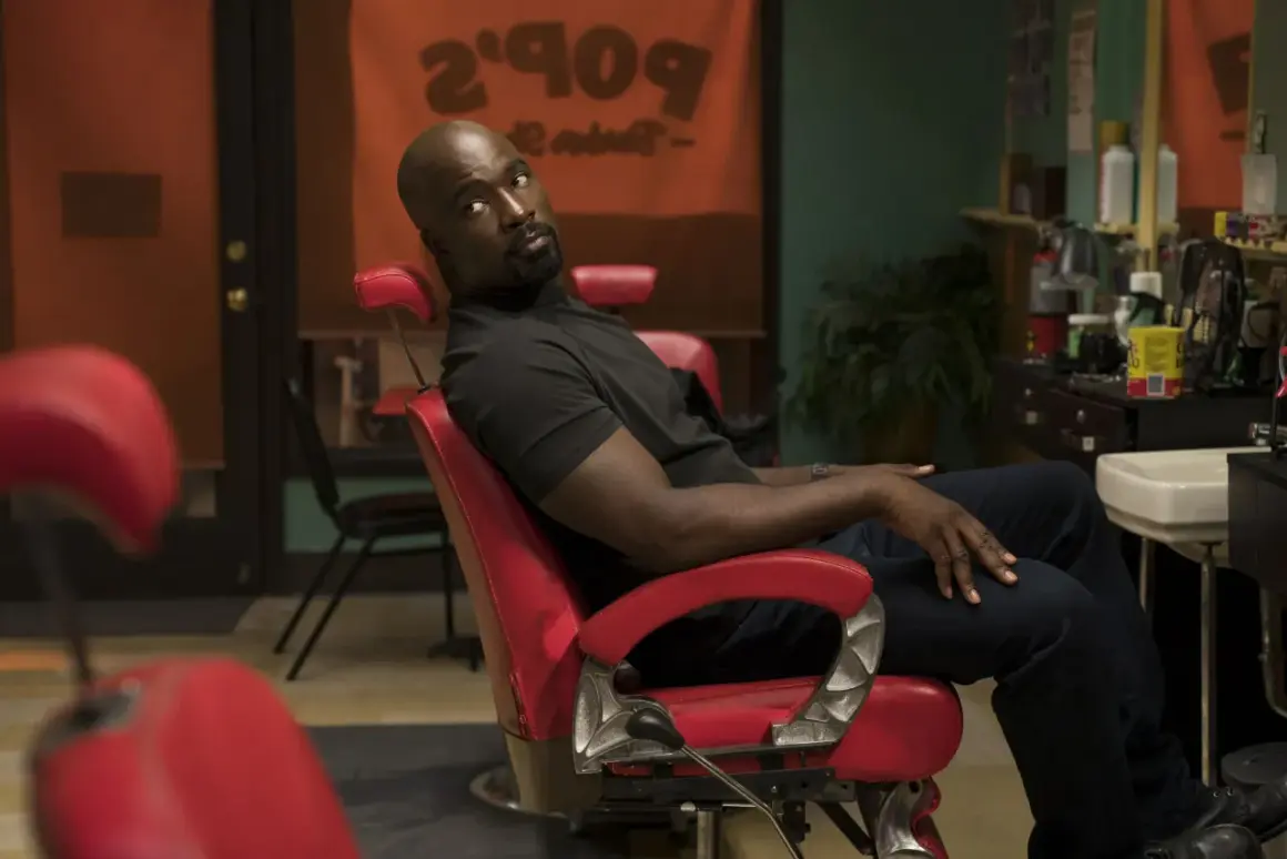 Luke Cage obsada: Mike Colter w czerwonym fotelu fryzjerskim, w tle szyld "Pop's Barber Shop".