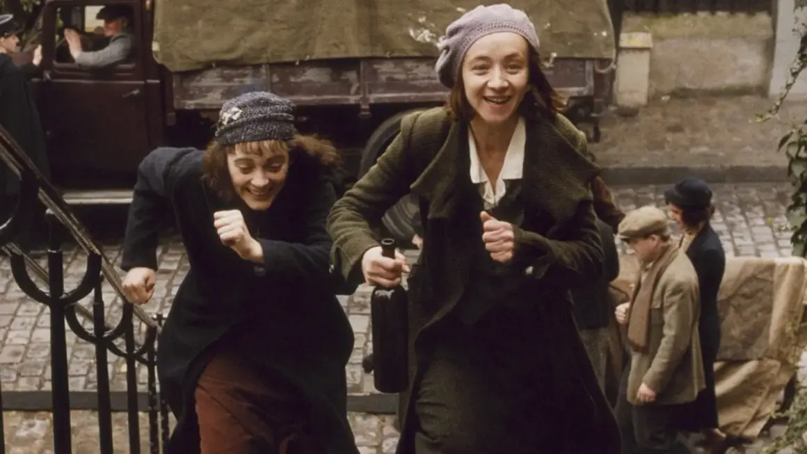 Dwie kobiety biegną po schodach, śmiejąc się radośnie. Jedna z nich trzyma butelkę wina. Bohaterka filmu niczego nie żałuje, ciesząc się chwilą.