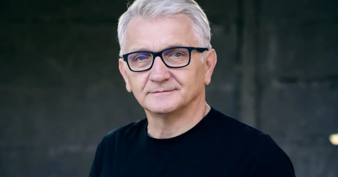 Portret Dariusza Kowalskiego, aktora, w okularach i czarnej koszulce.