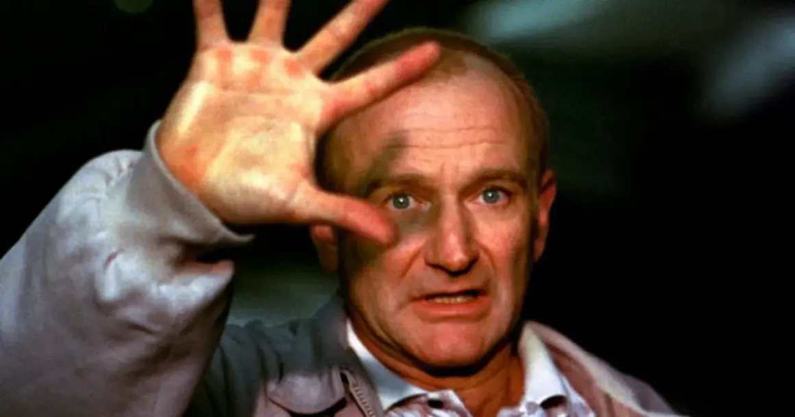 Robin Williams, który zdobył Oscara za rolę w "Buntowniku z wyboru", z dłonią przed twarzą.