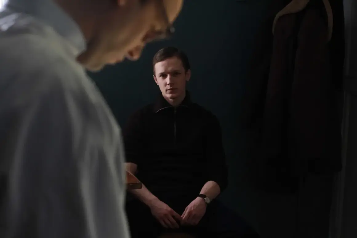 Filip Pławiak siedzi w ciemnym pomieszczeniu, wpatrując się wprost przed siebie.