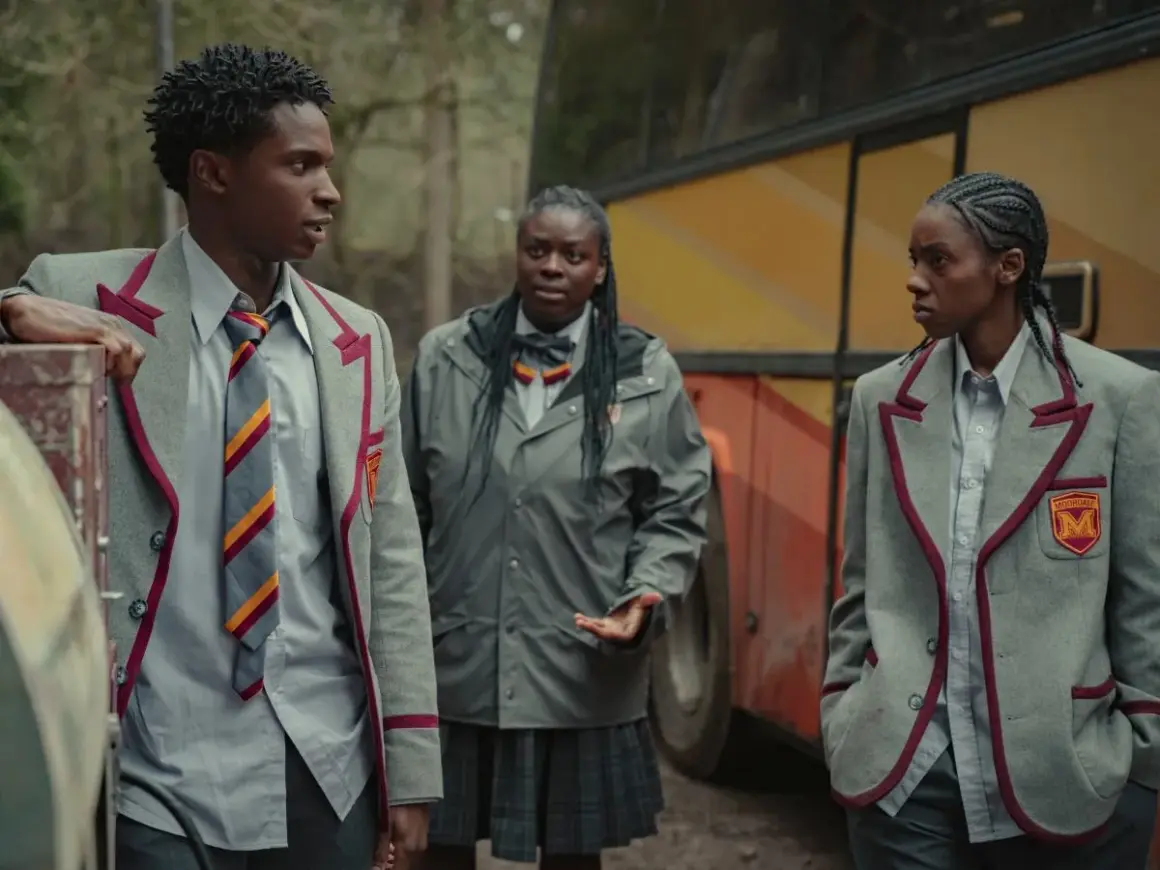 Kedar Williams Stirling i dwaj koledzy w szkolnych mundurkach stoją obok autobusu.