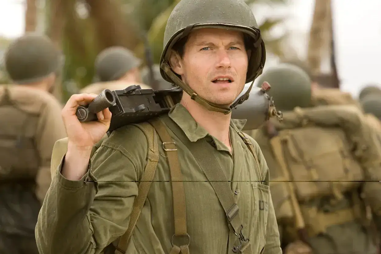 Żołnierz w hełmie, James Badge Dale, niesie broń na ramieniu, gotowy do walki.