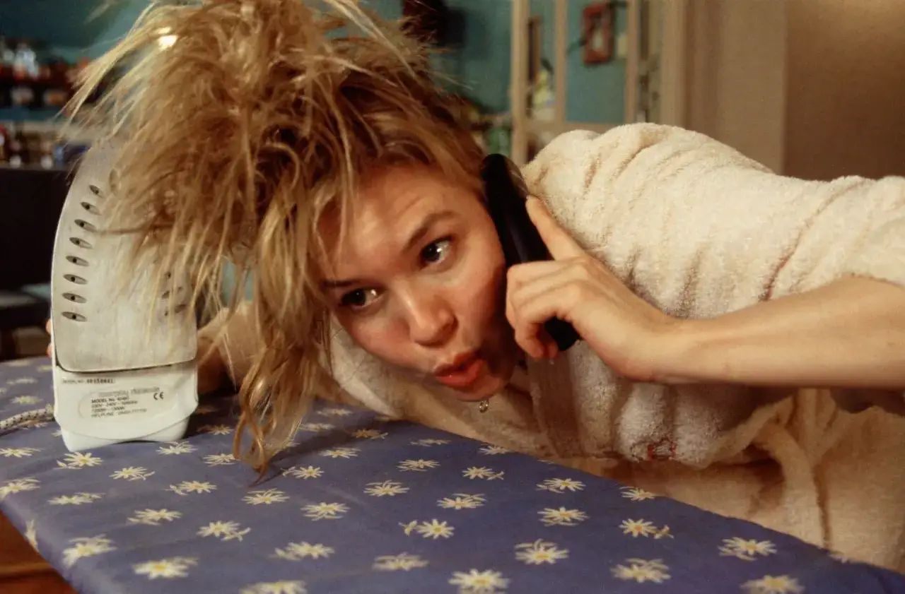 Bridget Jones w pogoni za rozumem: Renée Zellweger na desce do prasowania, rozmawiając przez telefon, z rozczochranymi włosami.