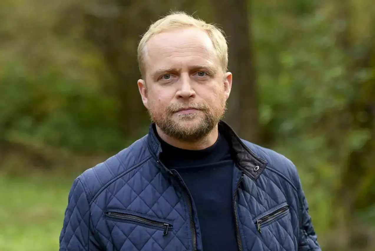 Mężczyzna w granatowej kurtce, zastanawiający się, ile zarabia aktor filmowy w Polsce.