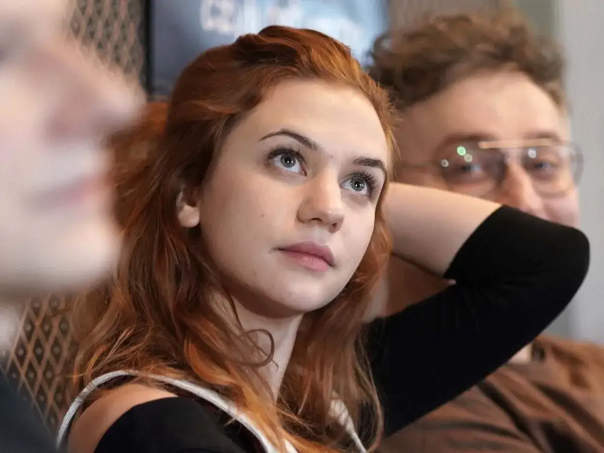 Młoda, rudowłosa Aleksandra Grabowska, aktorka, patrzy w górę, obok niej mężczyzna w okularach.