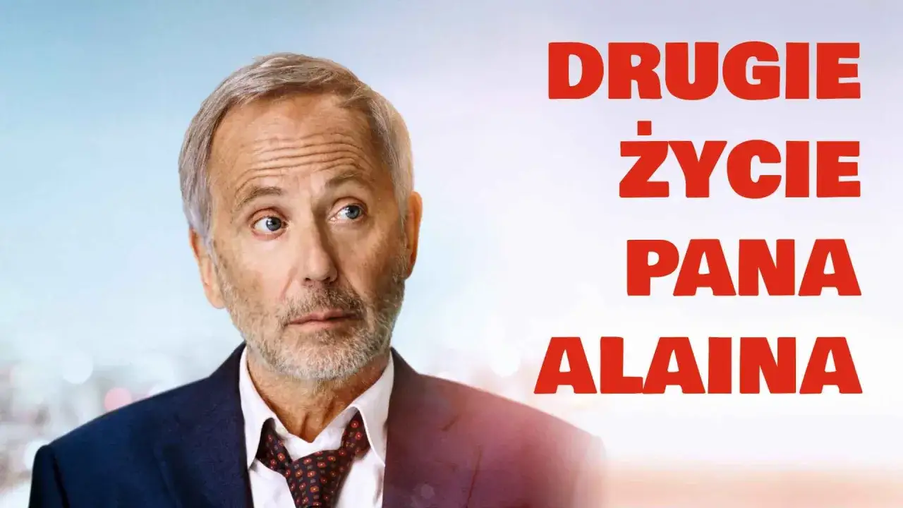 Pan Alain w garniturze, z siwymi włosami i zarostem, spogląda w bok. Obok widnieje napis
