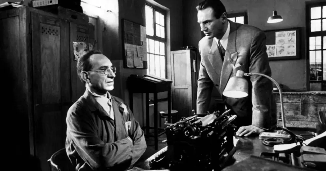 Oskar Schindler (Liam Neeson) rozmawia z Itzhakiem Sternem (Ben Kingsley) przy maszynie do pisania. Obsada Listy Schindlera w scenie.