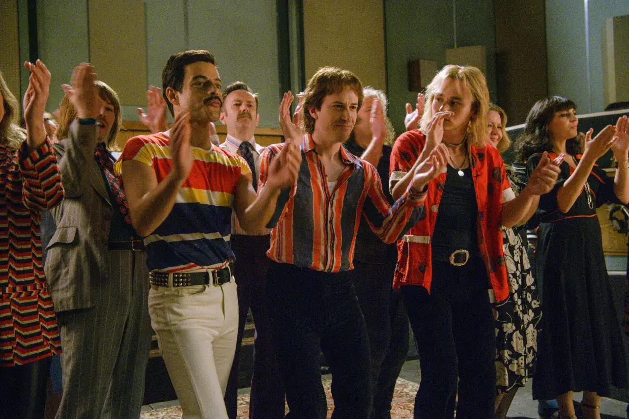 Bohemian Rhapsody obsada: Rami Malek jako Freddie Mercury i jego koledzy z zespołu świętują sukces.