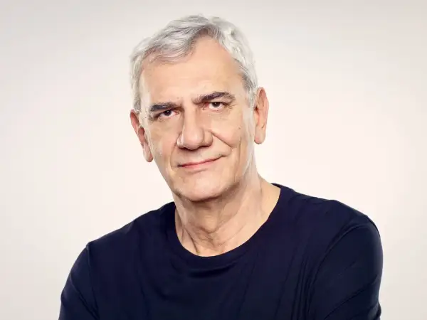 Wiktor Zborowski, z siwymi włosami i w granatowej koszulce, patrzy z uśmiechem w obiektyw.