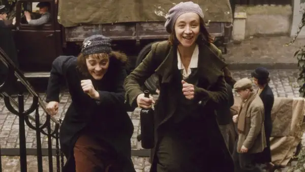 Dwie kobiety biegną po schodach, śmiejąc się radośnie. Jedna z nich trzyma butelkę wina. Bohaterka filmu niczego nie żałuje, ciesząc się chwilą.