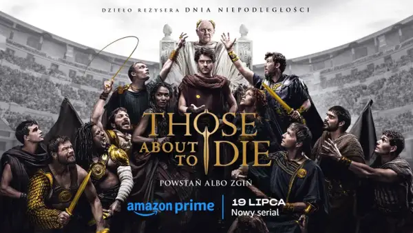 Obsada serialu Those About to Die w antycznych strojach, z gladiatorem w złotej zbroi na pierwszym planie.