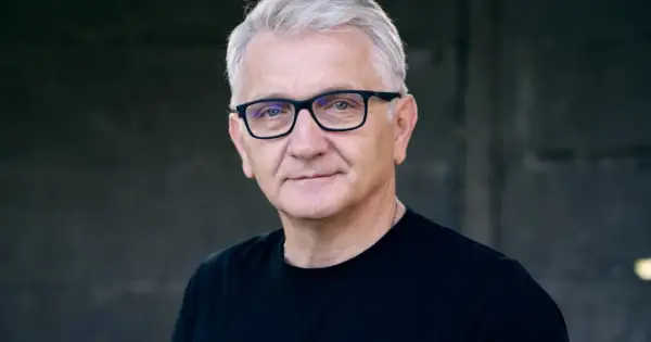 Portret Dariusza Kowalskiego, aktora, w okularach i czarnej koszulce.