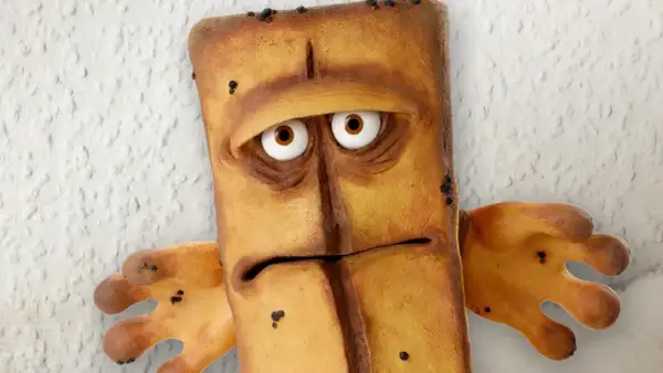 Smutny Bernd das Brot, z wielkimi oczami i wyrazem twarzy pełnym zmartwienia, stoi na tle chropowatej ściany.