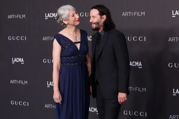 Alexandra Grant wzrost jest widoczny obok Keanu Reevesa. Oboje pozują na tle logo Gucci i Art+Film.