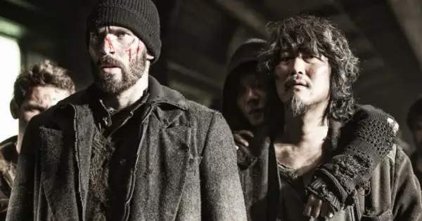 Zraniona obsada Snowpiercer: Arka przyszłości, w tym Chris Evans, w surowych, postapokaliptycznych strojach.