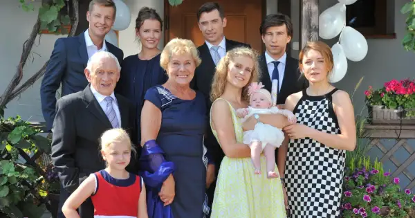 Rodzina z serialu "M jak miłość" pozuje do zdjęcia. Wszyscy uśmiechnięci, w tle balony i kwiaty.
