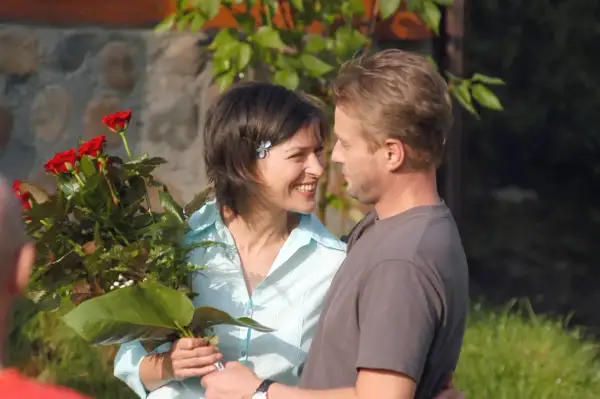 Uśmiechnięta kobieta z bukietem czerwonych róż patrzy na mężczyznę. Nigdy w życiu nie widział tak pięknego gestu.