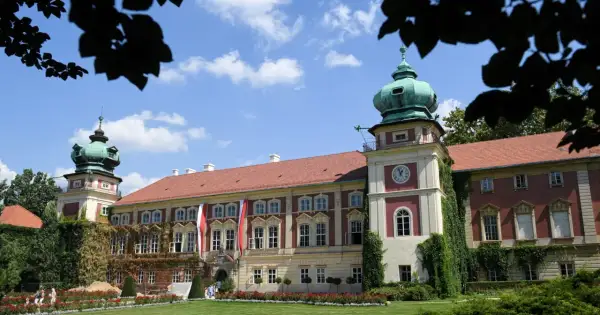 Pałac z zielonymi kopułami i zegarem, ozdobiony flagami, otoczony ogrodem.
