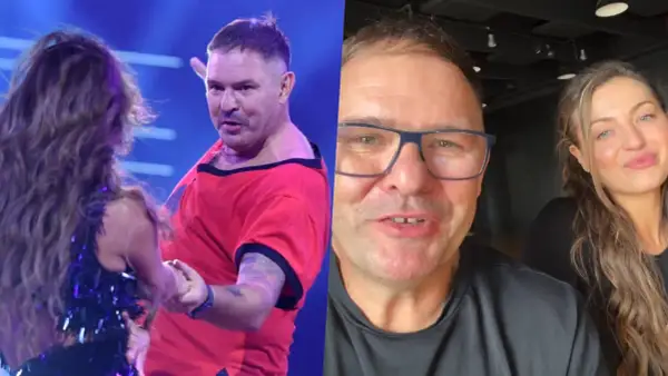 Tomasz Karolak tańczy na scenie w czerwonej koszulce i pozdrawia z uśmiechem w okularach. Obok niego uśmiechnięta kobieta.